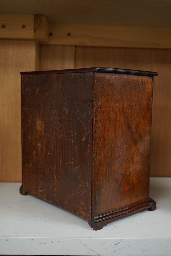 A late Georgian mahogany miniature four drawer chest. 23cm high, 21cm wide. Condition - good